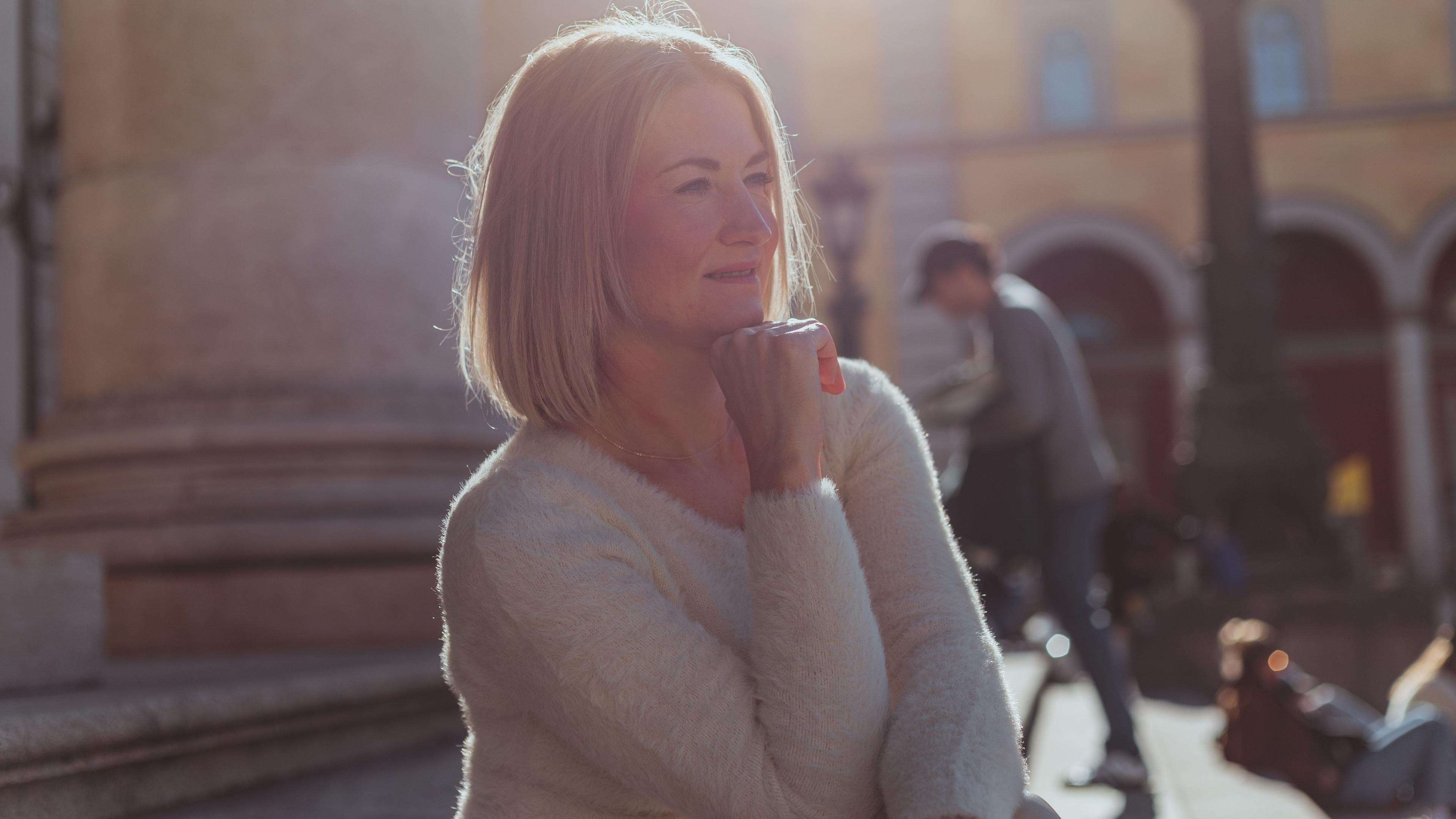 middle-aged woman with sun above head, looking comfortably
