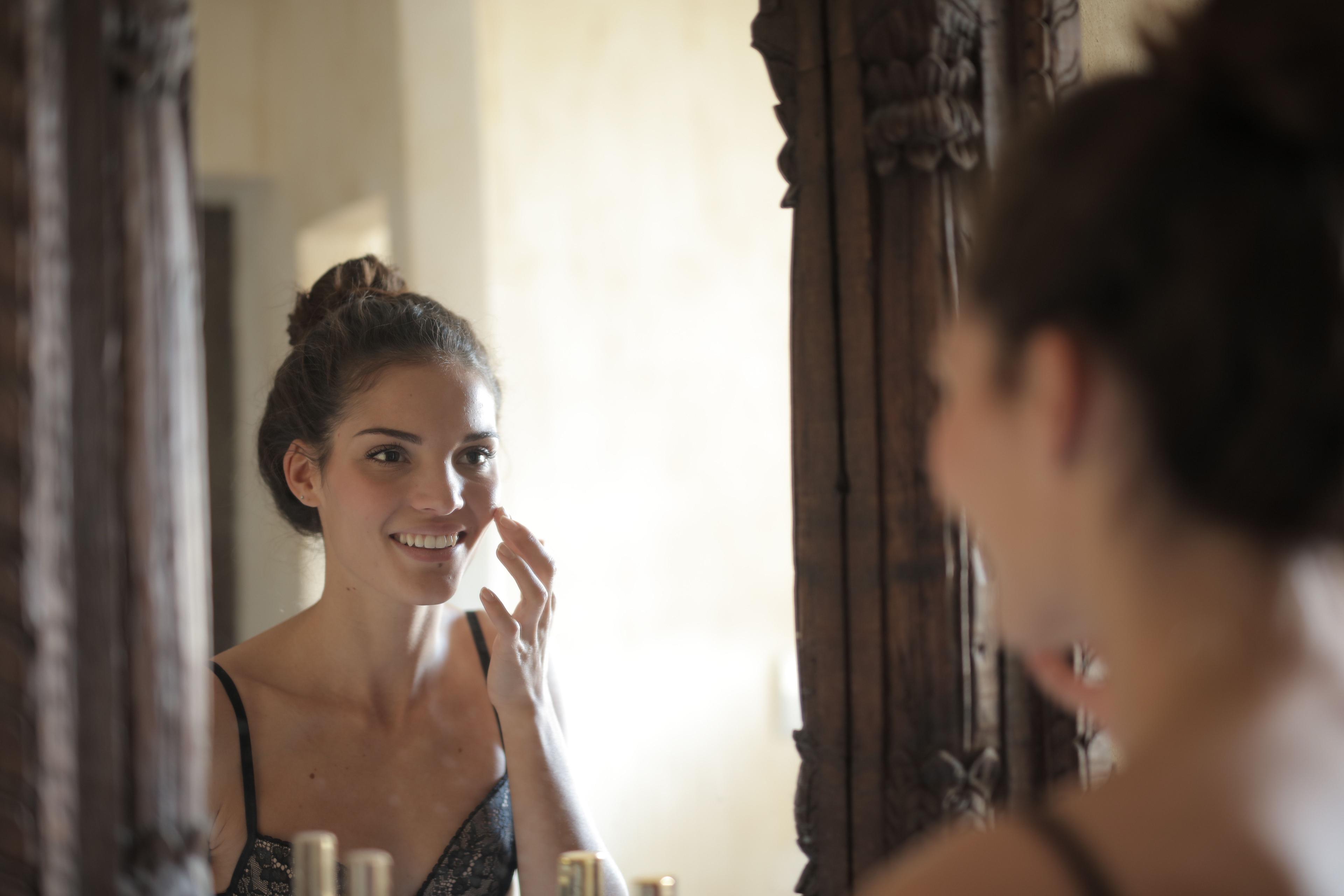 middle-aged woman taking care of her skin in mirror