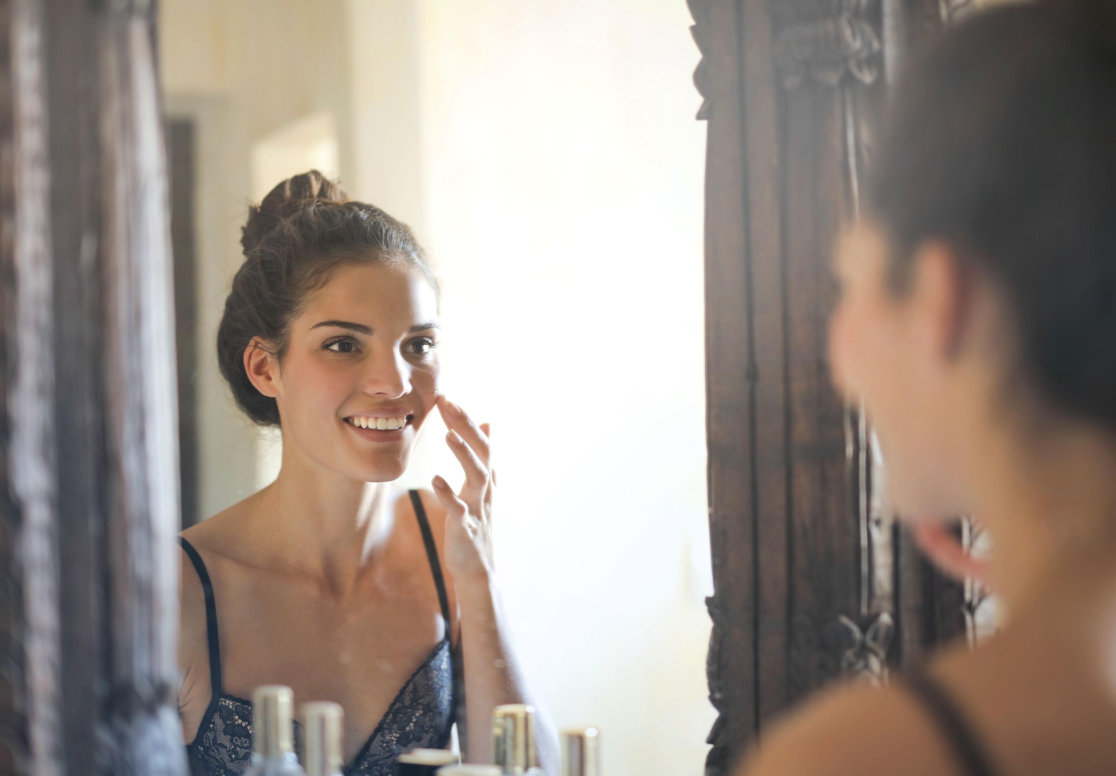 Younger mature lady taking care of her skin in mirror